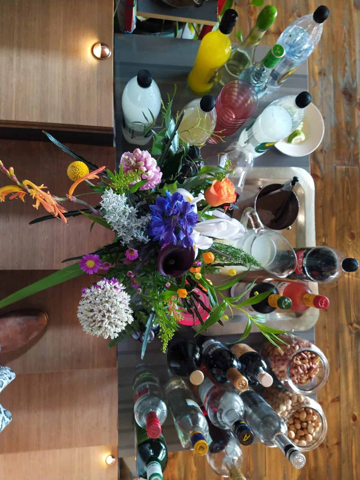 זר פרחים על שולחן עם הרבה יינות שתיה וכיבוד